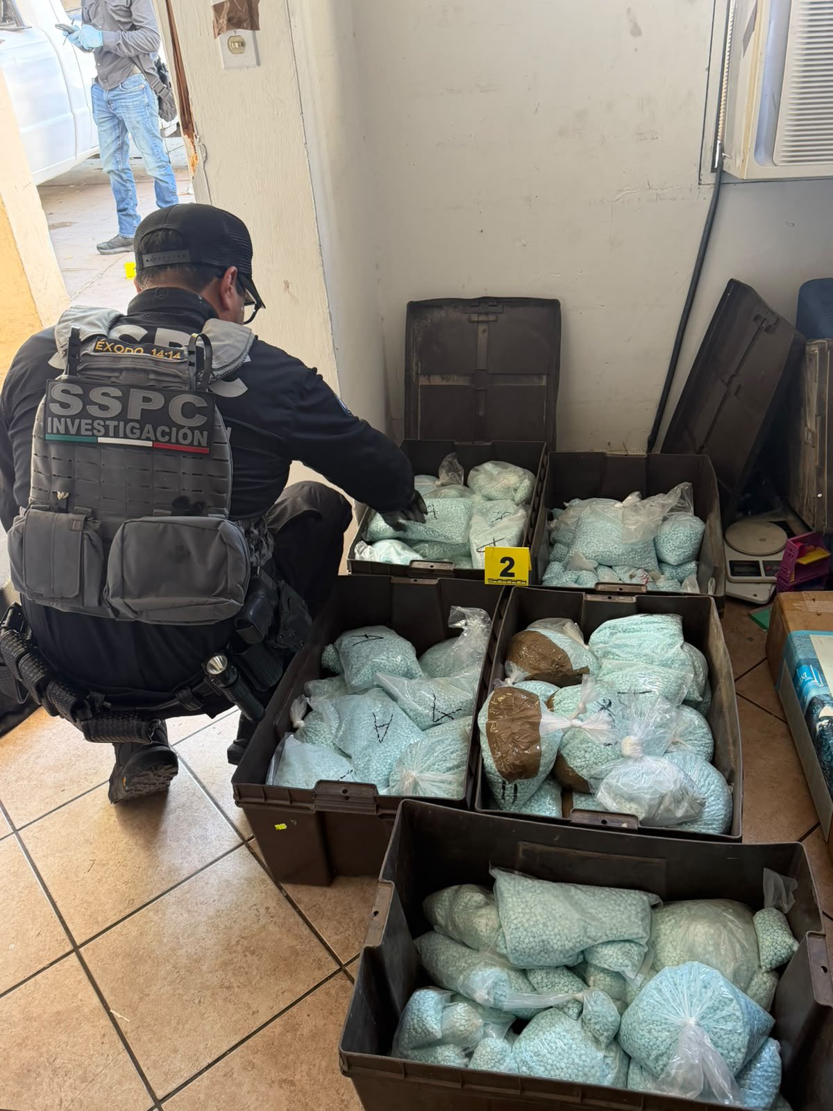 Agente de investigación observa bolsas con pastillas aseguradas dentro de un inmueble en Mexicali